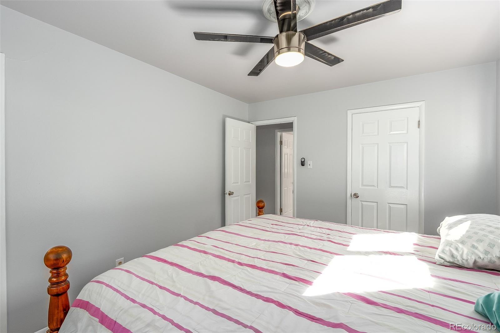 3217 South Stuart Street Denver, CO 80236 - Photo 21 of 30 a bedroom with a bed and a chandelier