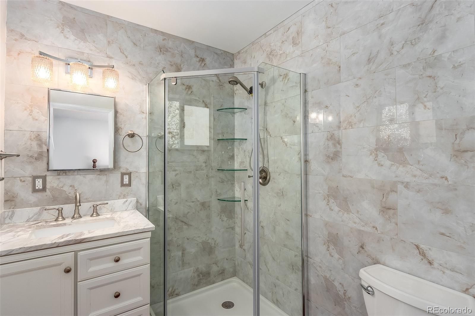 3217 South Stuart Street Denver, CO 80236 - Photo 22 of 30 a bathroom with a granite countertop sink a toilet and shower