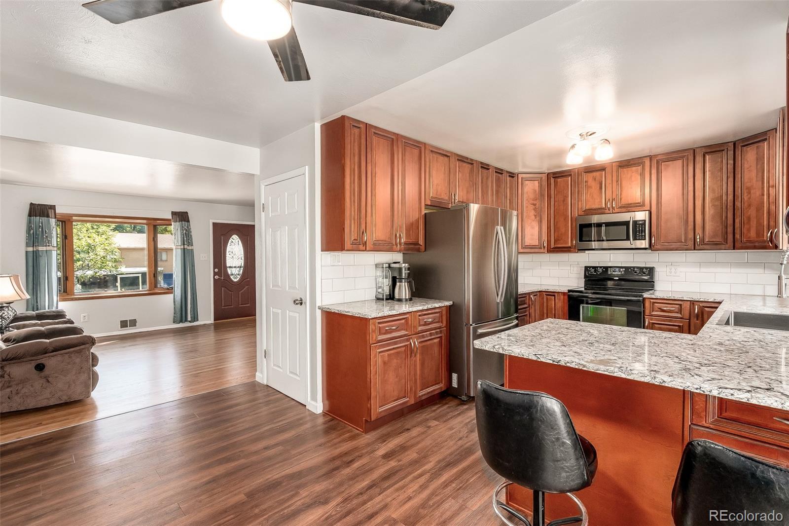 3217 South Stuart Street Denver, CO 80236 - Photo 4 of 30 a kitchen with granite countertop wooden floors a stove a sink and a center island