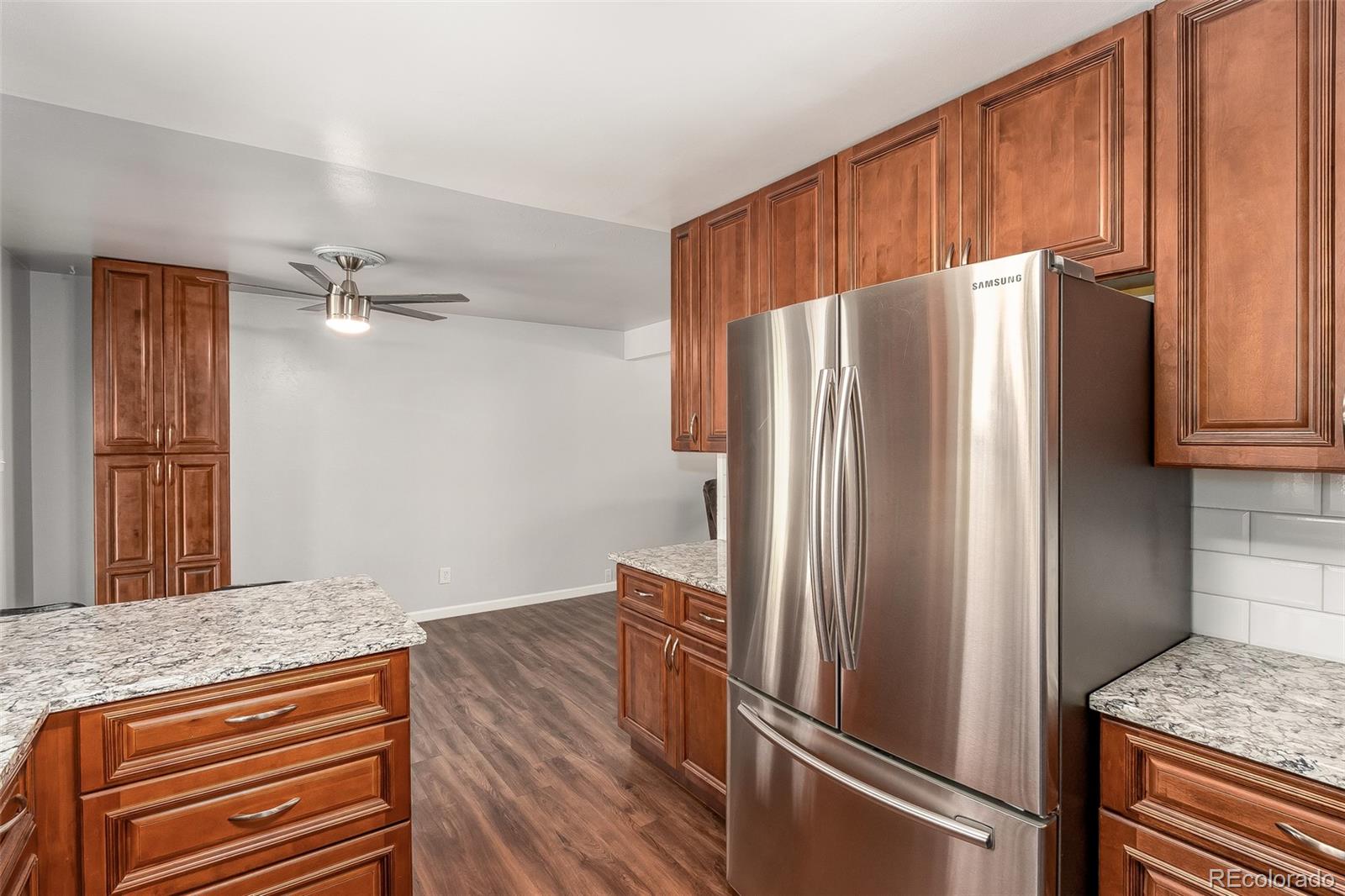 3217 South Stuart Street Denver, CO 80236 - Photo 5 of 30 a kitchen with granite countertop stainless steel appliances a refrigerator and cabinets