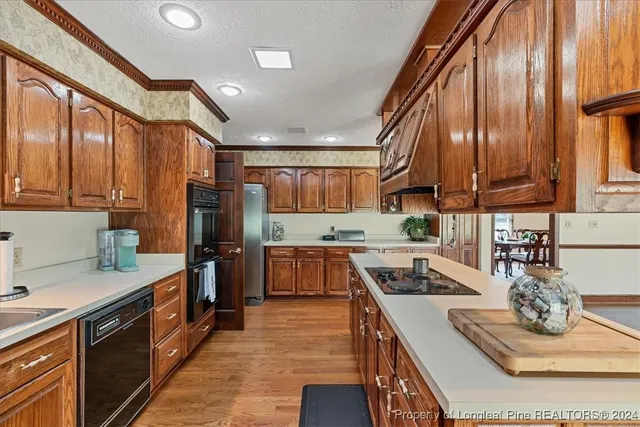 a kitchen with stainless steel appliances granite countertop a refrigerator a sink dishwasher and wooden cabinets with wooden floor