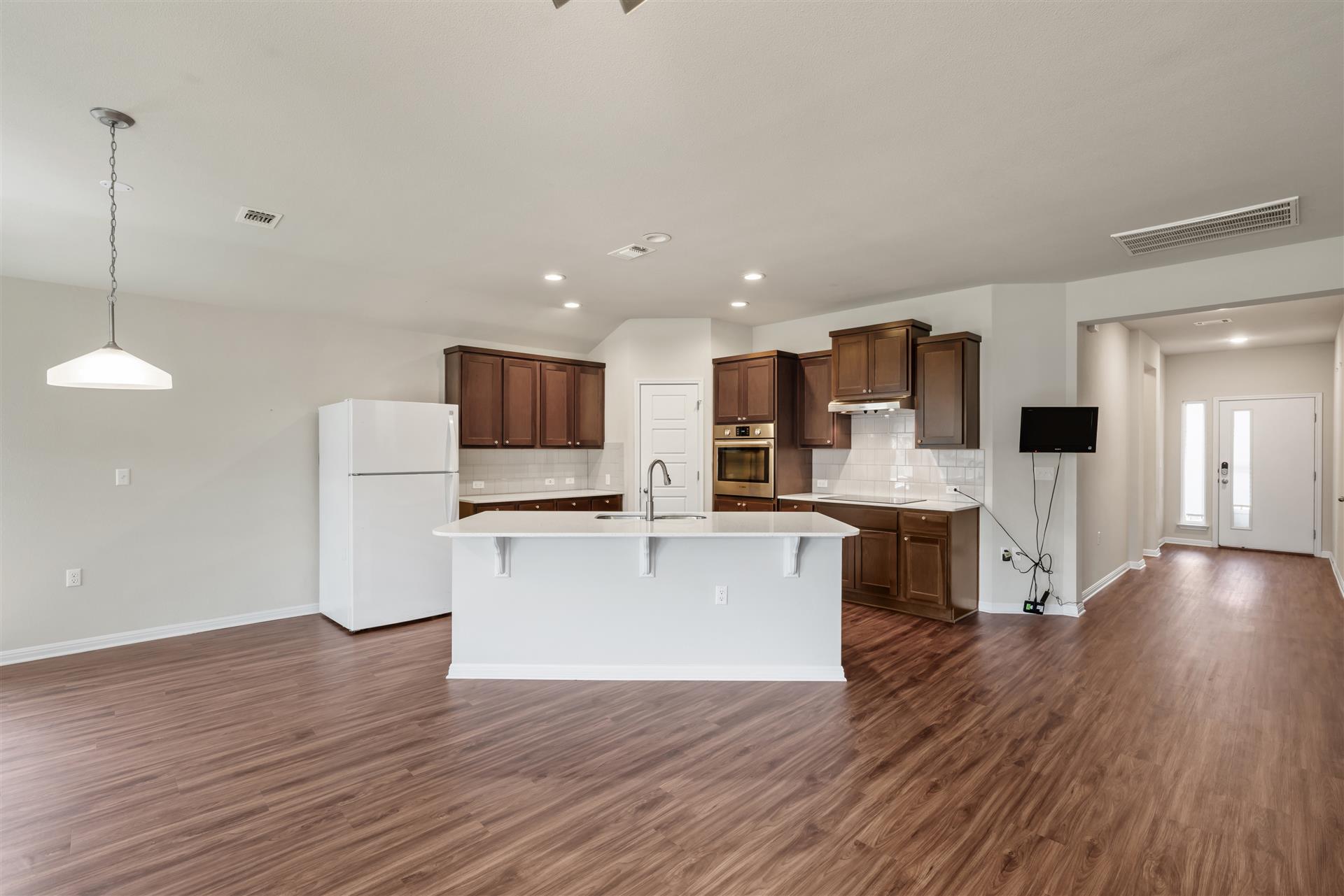 16512 Enamorado Road Manor, TX 78653 - Photo 21 of 31 A well-appointed kitchen island anchors this open concept living space, featuring rich wood cabinetry and durable flooring.