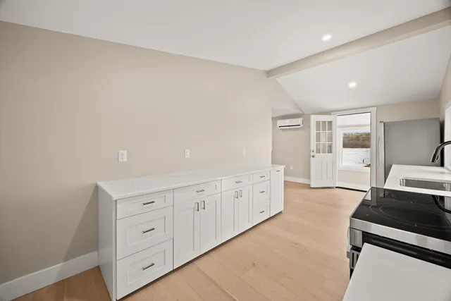 a kitchen with white cabinets and wooden floor