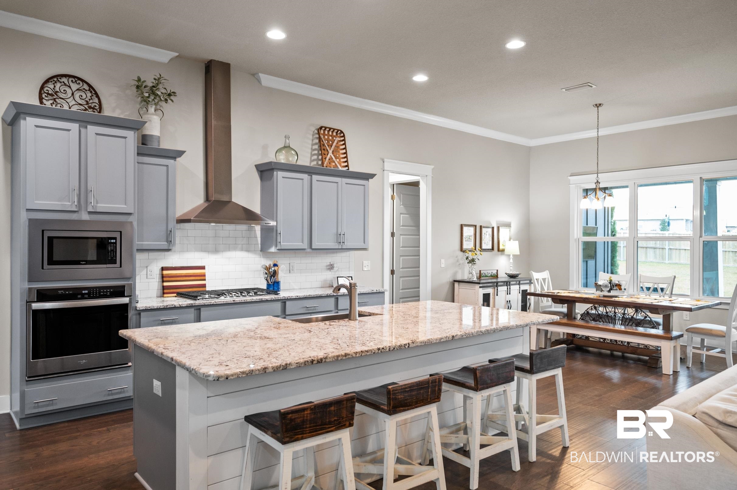 31355 Limpkin Street Daphne, AL 36527 - Photo 19 of 57 Kitchen featuring sink, wall chimney exhaust hood, an island with sink, light stone counters, and stainless steel appliances
