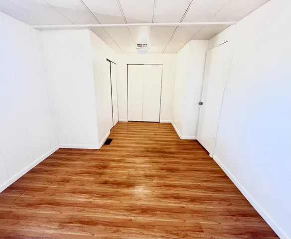 a view of a big room with wooden floor and entryway