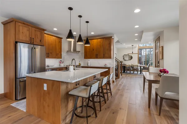 a kitchen with stainless steel appliances kitchen island granite countertop a table chairs refrigerator and microwave