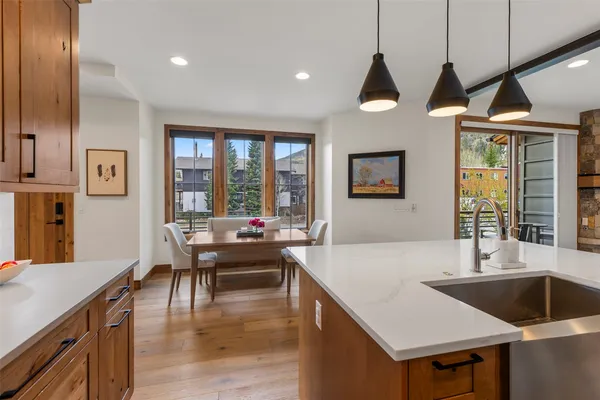 a kitchen with a stove a sink a dining table and chairs with wooden floor