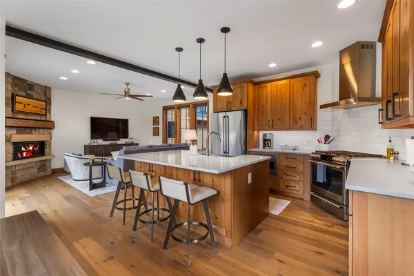 a kitchen with stainless steel appliances granite countertop a stove top oven a sink dishwasher a dining table and chairs with wooden floor