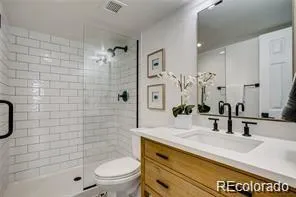 a bathroom with a granite countertop sink a toilet and shower