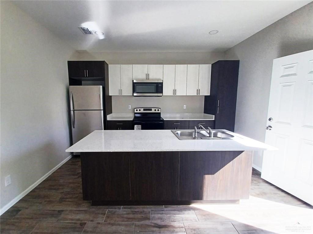 907 East Starr Road, Unit D Mercedes, TX 78570 - Photo 7 of 10 a kitchen with kitchen island stainless steel appliances a sink stove refrigerator and cabinets