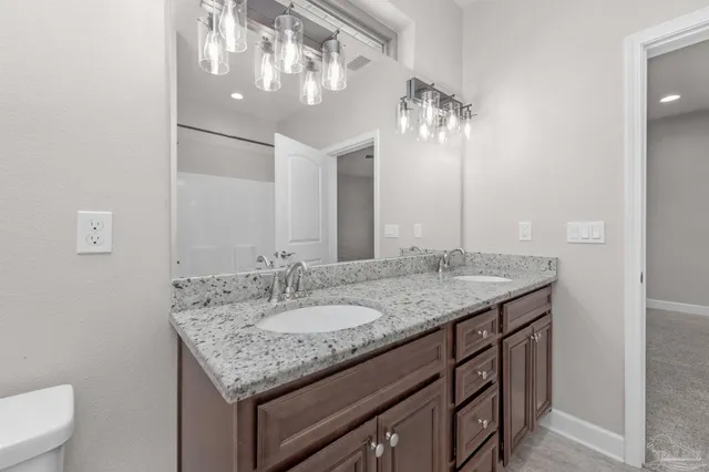 a bathroom with a granite countertop sink a toilet and a large mirror