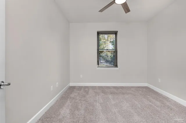 an empty room with ceiling fan and window