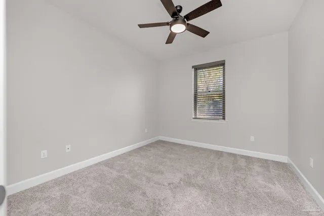 an empty room with a ceiling fan and carpet