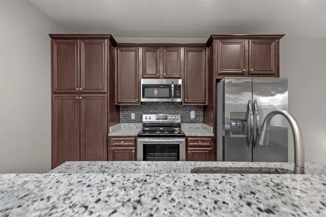 a kitchen with granite countertop a refrigerator and a stove top oven