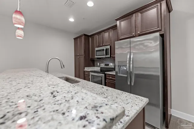 a kitchen with granite countertop a refrigerator and a sink