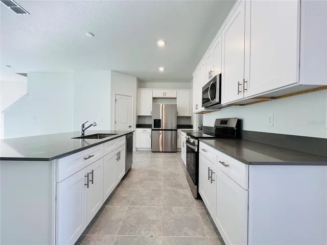 a large kitchen with stainless steel appliances granite countertop a sink and cabinets