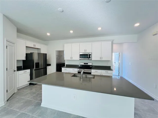 a large kitchen with a large counter top stainless steel appliances and cabinets