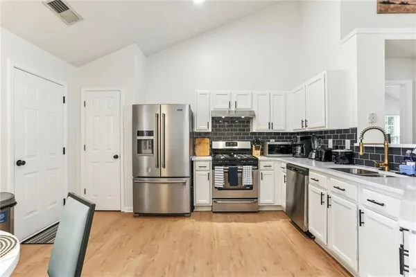 a kitchen with white cabinets and stainless steel appliances