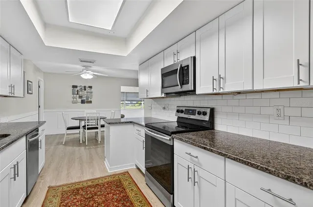 a kitchen with granite countertop a sink a stove and cabinets