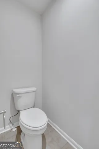 a white toilet sitting next to a white wall