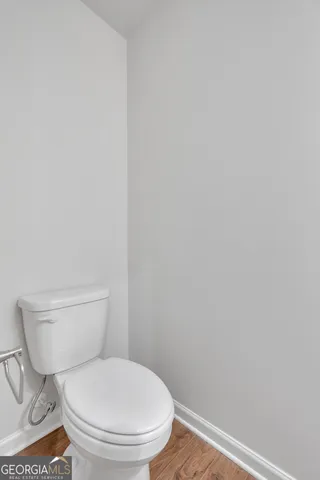 a white toilet sitting next to a white wall