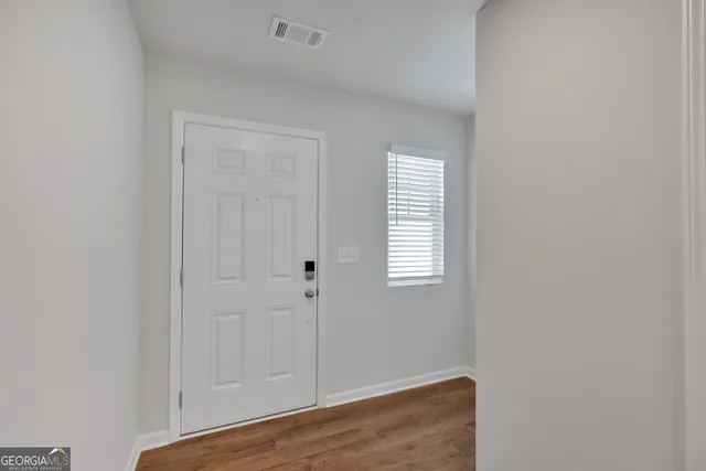 a view of an empty room with wooden floor and closet