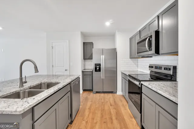 a kitchen with stainless steel appliances granite countertop a sink stove microwave and refrigerator