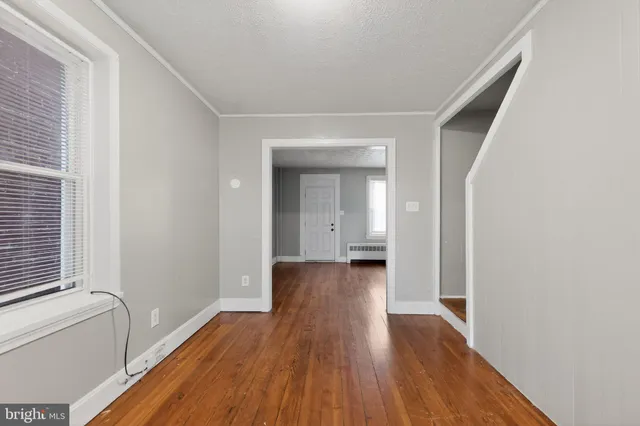a view of a hallway with wooden floor and a bathroom