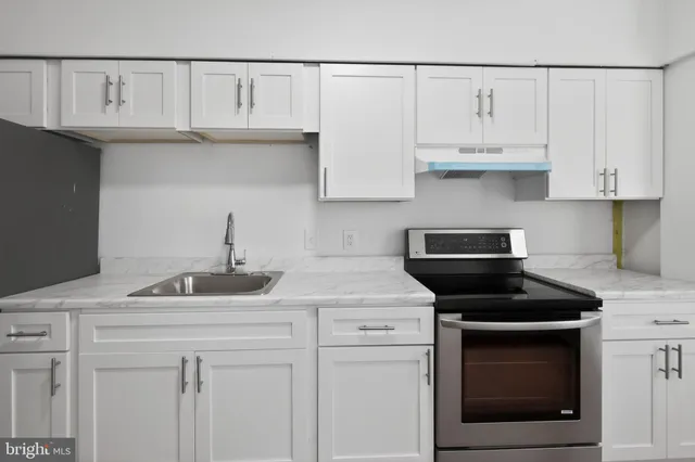 a kitchen with white cabinets and a stove with a sink