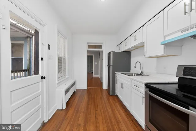 a kitchen with cabinets wooden floor and stainless steel appliances