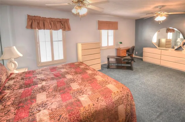 a spacious bedroom with a bed a chandelier and window