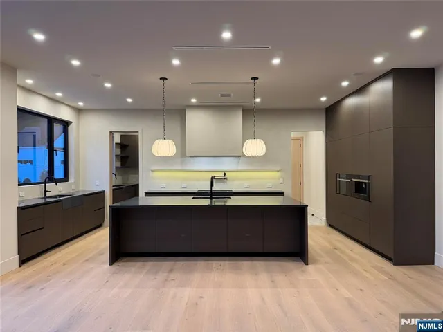 a large kitchen with stainless steel appliances a large counter top a stove and a sink