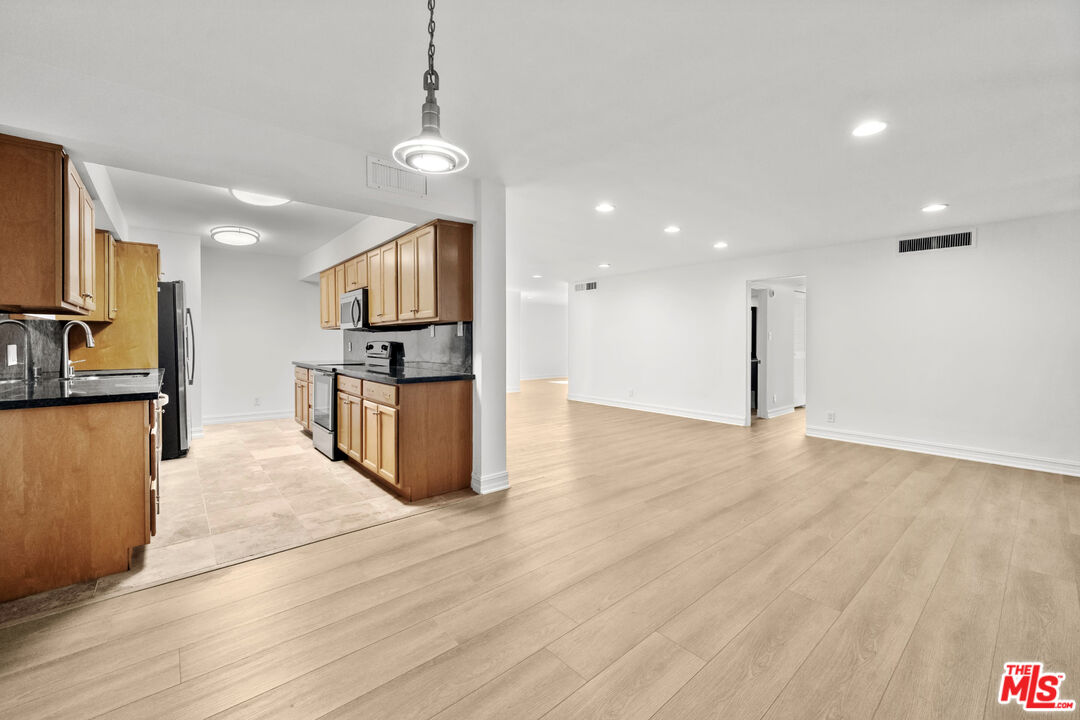 a kitchen with stainless steel appliances granite countertop a refrigerator a stove and a wooden floors