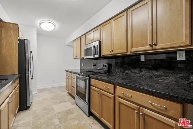 a kitchen with stainless steel appliances granite countertop a refrigerator a stove and a sink