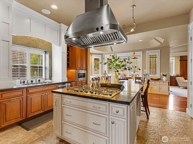 a kitchen with stainless steel appliances granite countertop a stove a sink a dining table and chairs with wooden floor