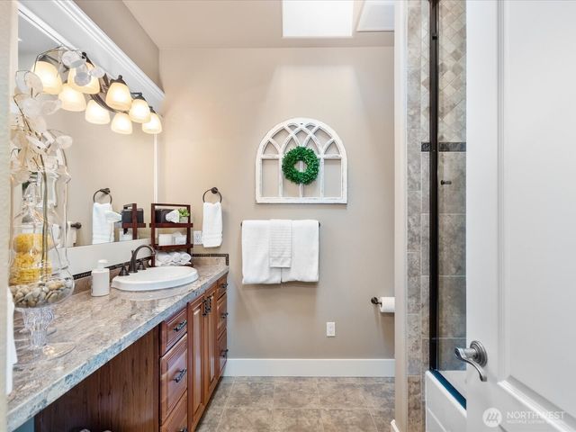 a bathroom with a granite countertop double vanity and a mirror