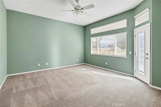 an empty room with windows and ceiling fan