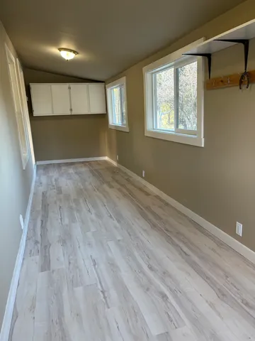 a view of empty room with wooden floor and fan