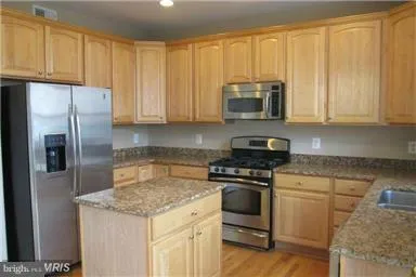 a kitchen with stainless steel appliances granite countertop a sink refrigerator and microwave