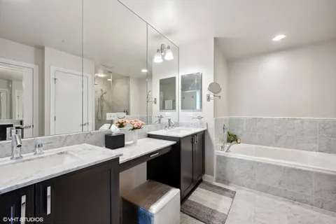 a bathroom with a sink double vanity granite tub shower and a mirror