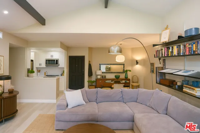 a living room with furniture kitchen view and a wooden floor
