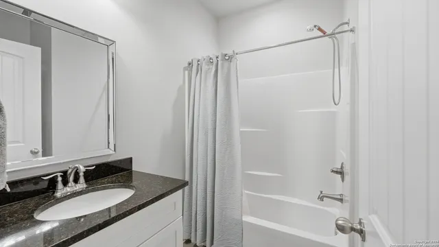 a bathroom with a granite countertop sink vanity mirror and shower