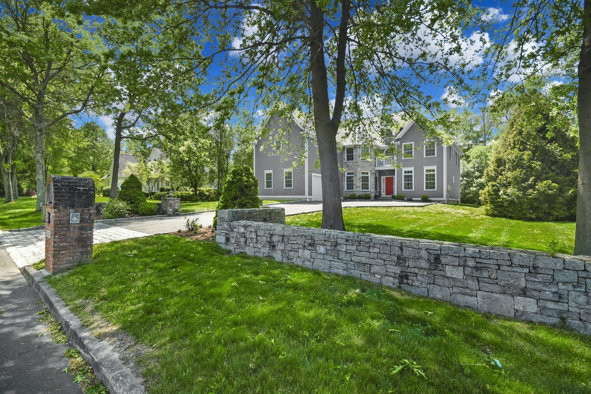 a front view of a house with garden and trees