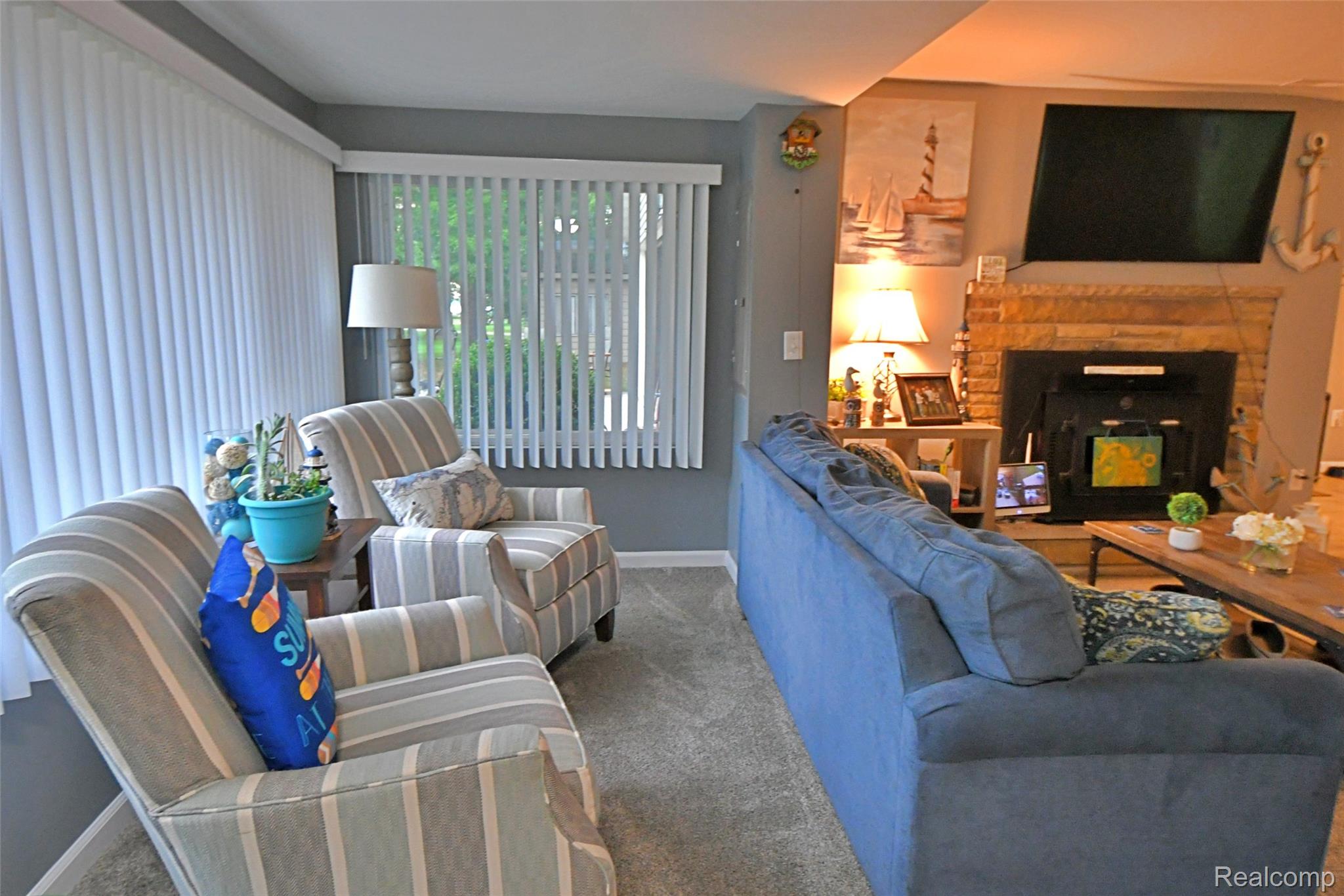 9611 Monroe Road St. Helen, MI 48656 - Photo 11 of 24 Living area featuring a stone fireplace with hearth, wall-mounted television, and neutral carpeting