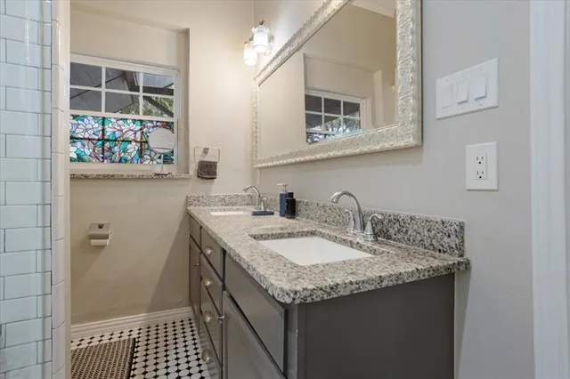 a bathroom with a granite countertop sink a mirror and a shower