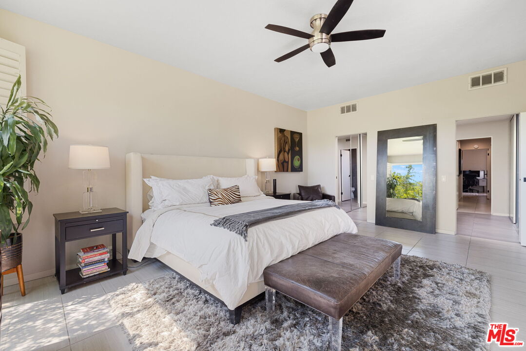 155 Desert W Drive Rancho Mirage, CA 92270 - Photo 28 of 50 a bedroom with a bed a mirror and a potted plant
