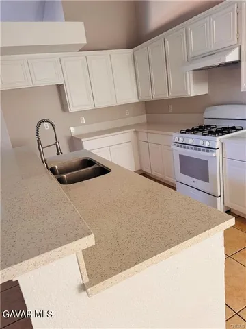 a kitchen with granite countertop a sink a stove and cabinets