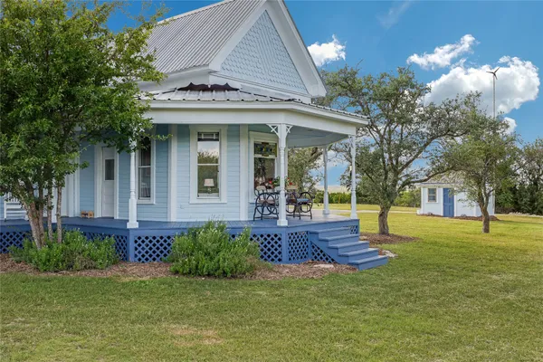 a front view of house with yard and trees in the background