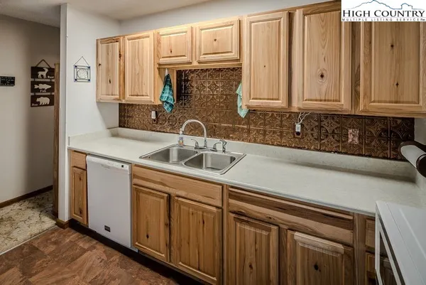 a kitchen with stainless steel appliances granite countertop a sink a stove and white cabinets with wooden floor