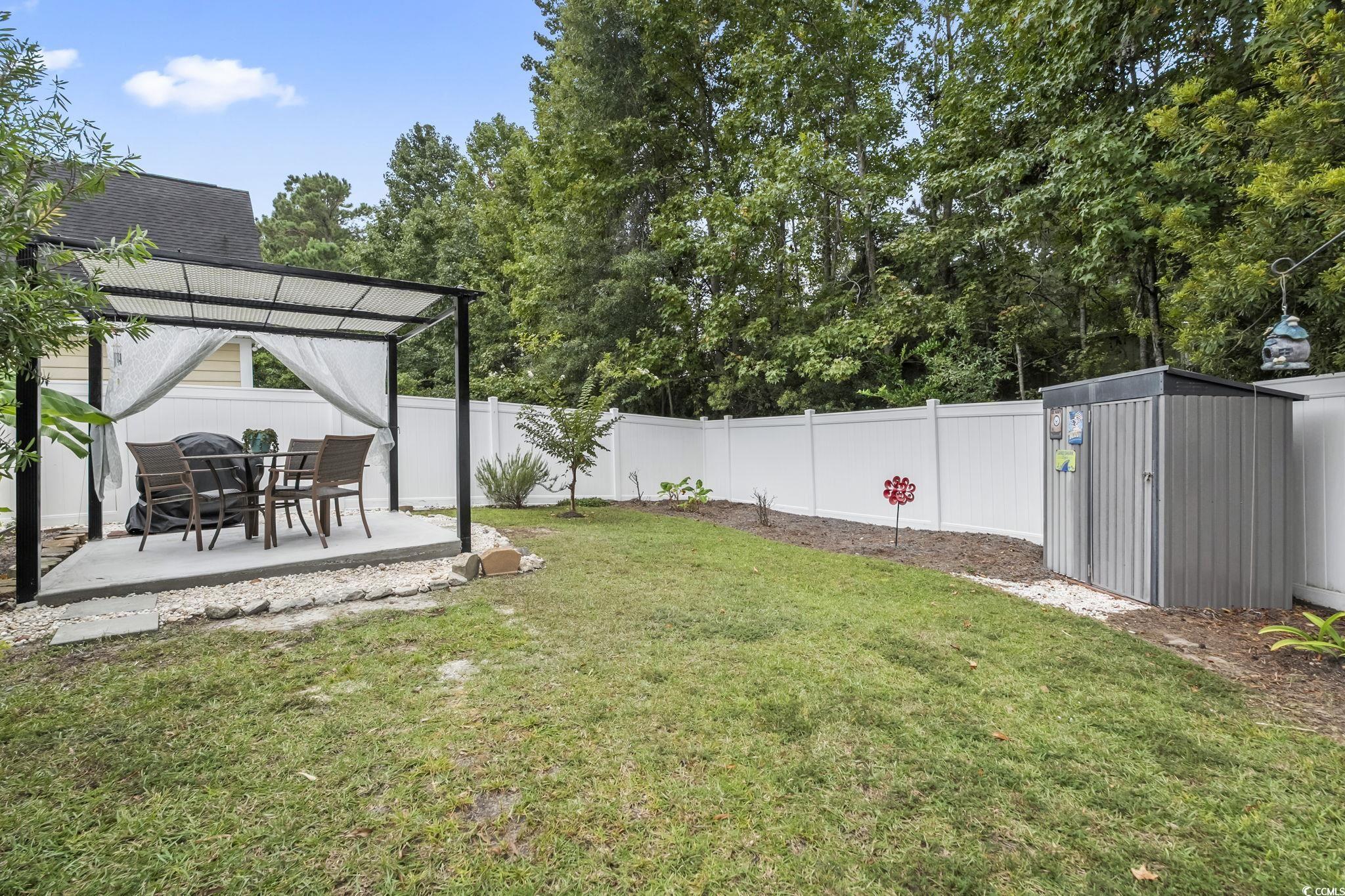 173 Foxpath Loop Myrtle Beach, SC 29588 - Photo 25 of 31 Fenced backyard featuring a patio area, a storage unit, and view of wooded area